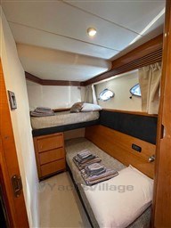 Cozy cabin interior of 2002 Princess V65 yacht with bunk beds and wooden accents.