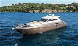 Luxurious 2002 Princess V65 yacht cruising on clear blue waters near a scenic coastline.