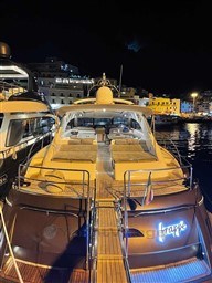 Luxury Princess V65 yacht docked at night, 2002 model, illuminated with city lights.