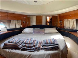 Luxurious 2002 Princess V65 yacht cabin with cozy bed and elegant wood finishes.