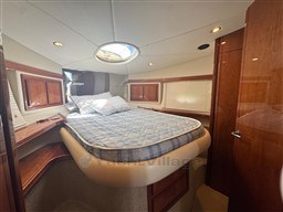 Luxurious cabin interior of 2002 Rodman 38fly yacht with cozy bed and wooden accents.