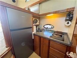 Compact kitchen in a 2002 Rodman 38fly yacht with modern appliances and wooden cabinetry.