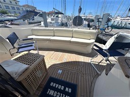Luxury seating area on a 2002 Rodman 38fly yacht, docked at a marina.