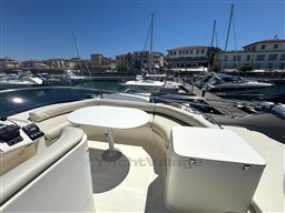 Rodman 38fly 2002 yacht with seating area, docked in a sunny marina.