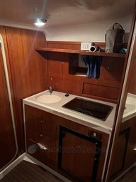 2011 Mano Marine 28.50 Sport boat interior with wooden cabinetry and compact kitchen area.