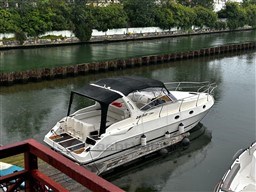2011 Mano Marine 28.50 Sport boat docked on a calm river with lush greenery.