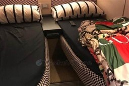 Twin beds with checkered bedding in a 2006 Azimut Atlantis 55 yacht cabin.