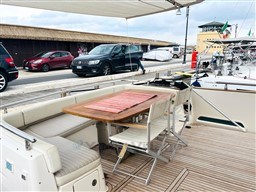 Outdoor seating area on 2011 Azimut Magellano 50 yacht, docked near vehicles.