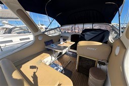 Interior of 2007 Mano Marine 24.50 boat with seating and table, docked at marina.