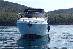 2007 Mano Marine 24.50 boat on calm water with forested hills in the background.
