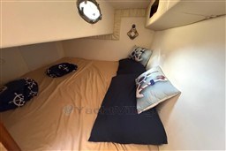 Cozy cabin interior of 2007 Mano Marine 24.50 with nautical-themed pillows and bedding.