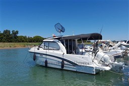 2022 Beneteau Antares 8 Fishing boat docked in serene waters under clear blue sky.