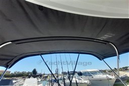 2022 Beneteau Antares 8 Fishing boat canopy with fishing rods in marina.