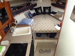 2009 Carolina Classic 28 cabin interior with cozy bed, kitchenette, and nautical decor.