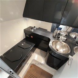 Compact kitchen area in a 1989 Tecnomar Benetti 50 offshore yacht, featuring sleek black cabinetry.