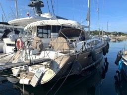2011 Jeanneau 53 yacht docked in marina, featuring sleek design and covered cockpit.