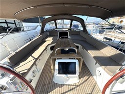 Spacious cockpit of 2011 Jeanneau 53 sailboat with cushioned seating and wooden table.