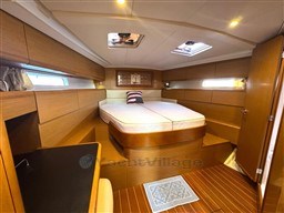 Luxurious 2011 Jeanneau 53 yacht cabin with wood finish and cozy bed.
