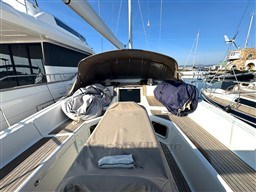 2011 Jeanneau 53 sailboat cockpit with covered seating, docked at marina under clear blue sky.