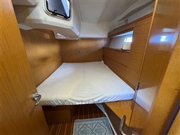 Cabin interior of 2011 Jeanneau 53 yacht with wooden finish and cozy bed.