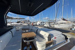 Luxurious 2023 Invictus TT 420 yacht interior at marina, featuring elegant seating and wooden tables.