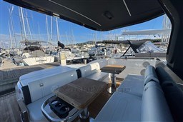 2023 Invictus TT 420 yacht interior with seating and tables, docked at a marina.