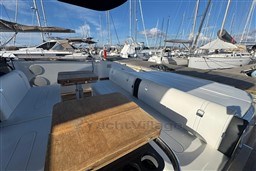 2023 Invictus TT 420 yacht interior with wooden table and white seating in marina.