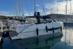 2023 Invictus TT 420 yacht docked in a marina, surrounded by sailboats.