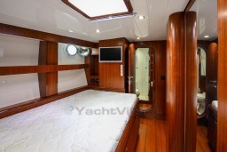Luxurious wooden cabin interior of 1978 Stain 70 Gulet yacht with bed and porthole.
