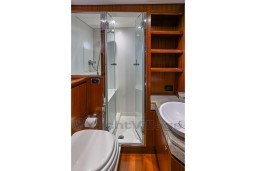 Luxurious bathroom on 1978 Stain 70 Gulet yacht with shower, sink, and wooden cabinetry.