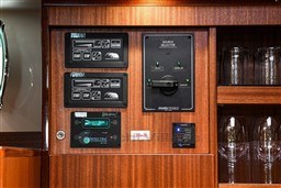 Control panel on 1978 Stain 70 Gulet yacht with wooden cabinetry and glassware.