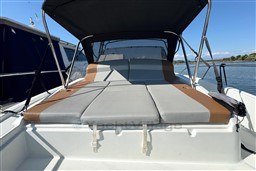 2024 Beneteau Flyer 9 SUNdeck boat with cushioned sunbathing area and canopy on calm water.