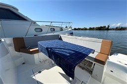 2024 Beneteau Flyer 9 SUNdeck boat with outdoor seating and table, docked by calm waters.