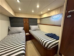 Twin cabin interior of 2006 Sunseeker Portofino 53 yacht with striped bedding.