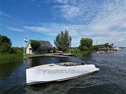 2024 VanDutch 32 Diesel yacht cruising on a scenic lake with houses and flags.