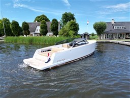 2024 VanDutch 32 Diesel boat cruising on a serene lake near charming houses.
