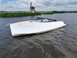 2024 VanDutch 32 Diesel boat on a river with a windmill in the background.