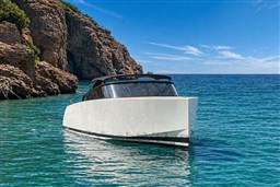 2017 VanDutch 40 yacht cruising in clear blue waters near rocky cliffs.