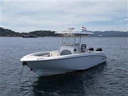 2005 Boston Whaler 320 Outrage boat anchored on calm water with scenic background.