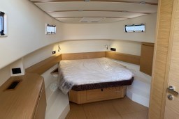 Interior cabin of 2022 Pardo Yachts P43, featuring a cozy bed and wooden accents.