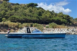 Wally 45 yacht from 2004 on blue water, with lush green trees in the background.