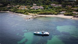 Aerial view of a 2004 Wally 45 boat near a scenic coastal village.