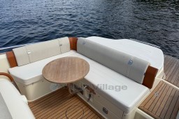Luxury seating area on 2023 Invictus GT 280 boat with wooden table and water view.