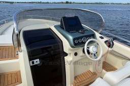 2023 Invictus GT 280 boat cockpit with modern controls and wooden deck, on a serene water backdrop.