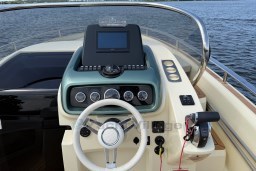 2023 Invictus GT 280 boat dashboard with steering wheel and control panel on water.