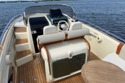 2023 Invictus GT 280 boat interior with helm, seating, and wooden deck on water.