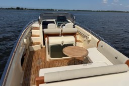 2023 Invictus GT 280 boat interior with wooden deck and seating on a calm lake.