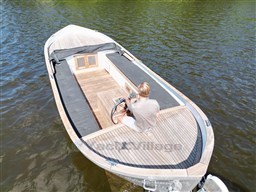 Vintage 1978 Sloop 785 boat on water, person steering, wooden deck, serene setting.