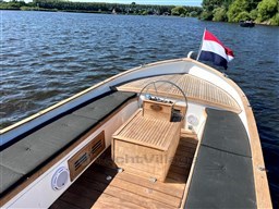 1978 Sloop 785 boat with wooden deck, black seating, and flag on a calm lake.