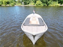 1978 Sloop 785 boat on calm water, surrounded by lush greenery and a windmill.